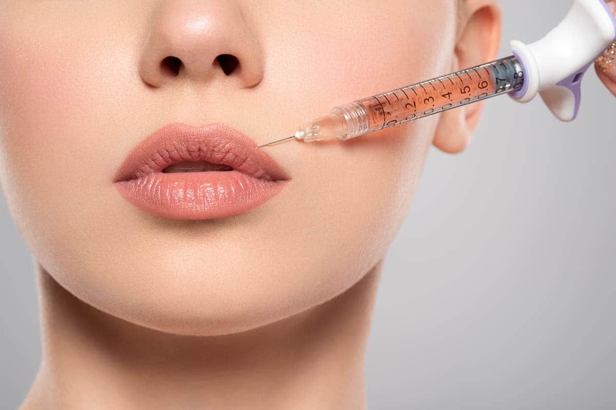 Woman getting cosmetic injection of filler in lips