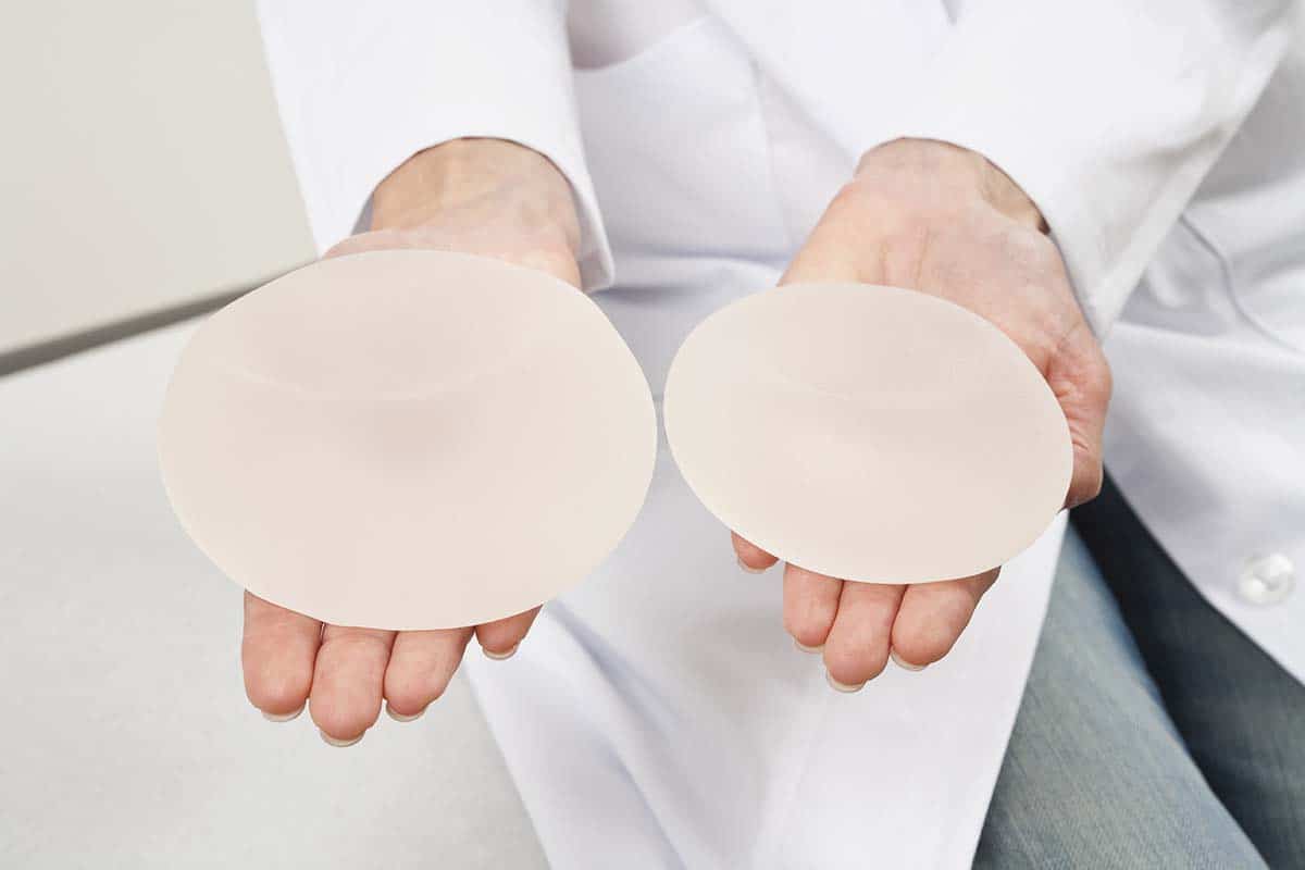 plastic surgeon holding two breast implants in his hands