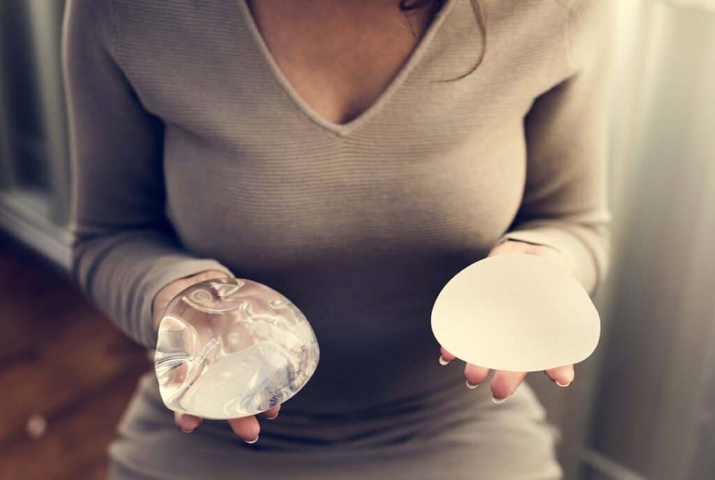 woman holding two breast implants