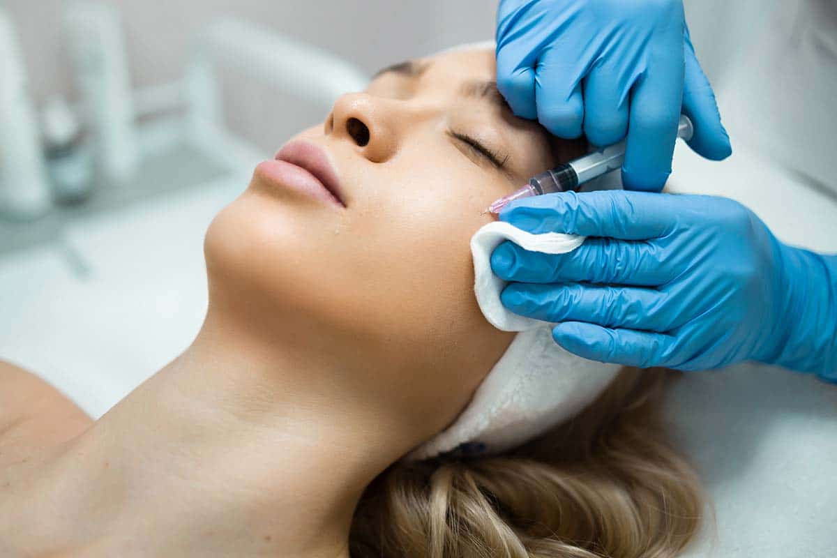 woman getting botox or dermal filler injection under eye