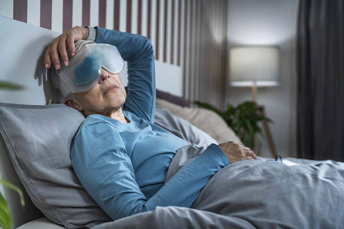 asian woman in bed wearing dark eye circle treatment eye mask