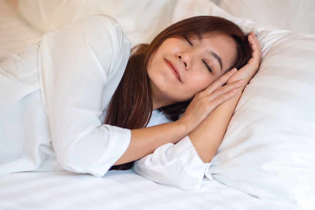 A beautiful woman sleeping in a white cozy bed at home