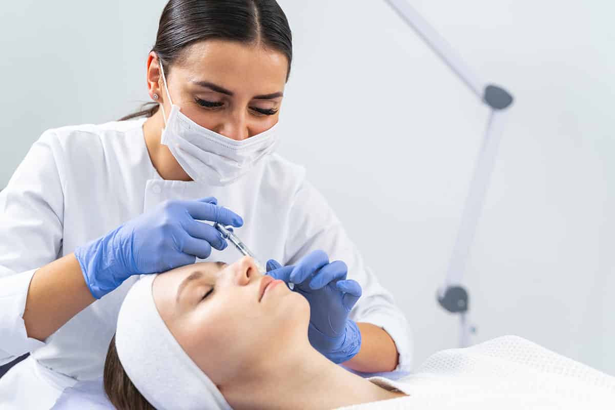 Dermatologist injecting a cheek filler to a woman