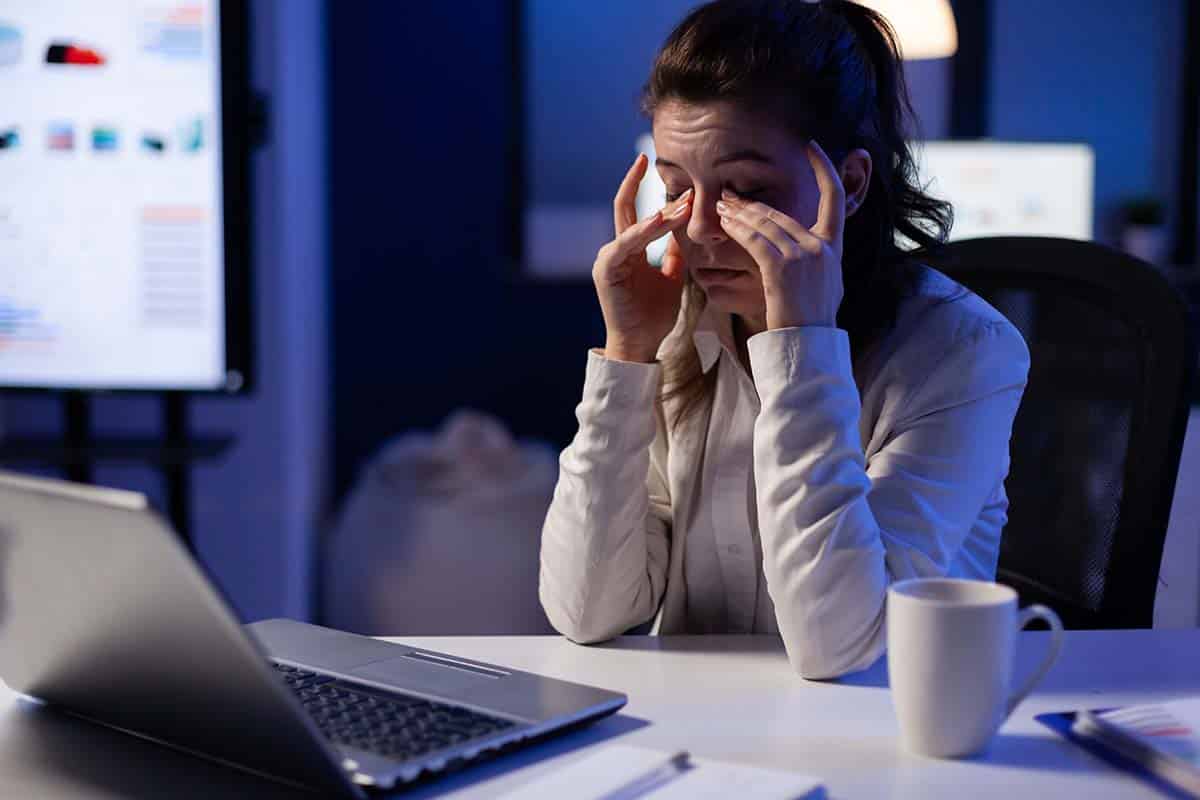 woman rubbing her tired eyes, covering her dark eye circles with hands